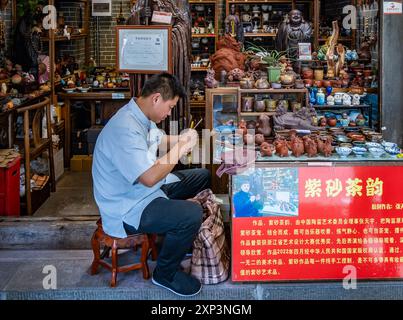 Un uomo che fa artigianato con l'argilla davanti a un negozio. Chengdu, Sichuan, Cina. Foto Stock