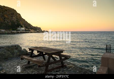 Tramonto su una spiaggia costiera mediterranea le onde si tuffano contro le rocce colorate Foto Stock