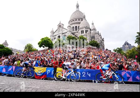 Il gruppo passa davanti alla Basilique du Sacre Coeur de Montmartre durante la gara ciclistica maschile dell'ottavo giorno dei Giochi Olimpici di Parigi del 2024 in Francia. Data foto: Sabato 3 agosto 2024. Foto Stock