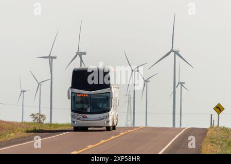 Autobus a due piani su strada rurale con turbine eoliche sullo sfondo nebbioso Foto Stock