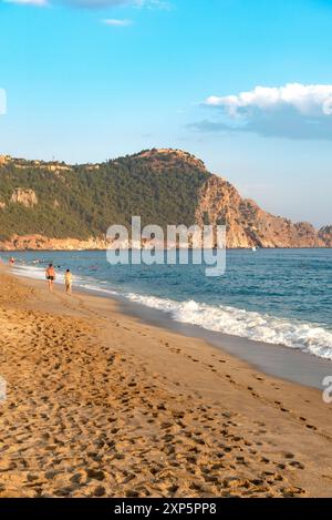 Alanya, Turchia. 9 luglio 2024. Una coppia cammina lungo una spiaggia vuota di Cleopatra al tramonto nella località turistica turca di Alanya, sulla costa mediterranea della Turchia, la riviera turca. (Foto di John Wreford/SOPA Images/Sipa USA) credito: SIPA USA/Alamy Live News Foto Stock