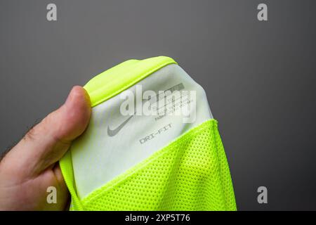 Parigi, Francia - 30 giugno 2024: Uomo che tiene una t-shirt Nike Dri-FIT gialla, con il logo, l'etichetta XL e "Made in Vietnam" sull'etichetta del capo Foto Stock