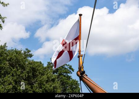 Croce di San Giorgio, bandiera di nave britannica che sventola alla prua di una nave ricostruita degli anni '1600, utilizzata per viaggiare nel nuovo mondo dagli esploratori. Foto Stock
