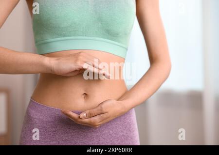 Digestione sana. Donna che tiene qualcosa vicino alla pancia dentro, primo piano Foto Stock