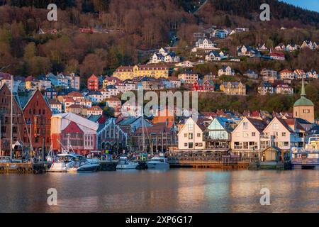 Bergen, Norvegia - 30 aprile 2024: Bergen, l'iconico Bryggen Quay norvegese con i suoi colorati edifici in legno, è affollata di gente. Le barche sono attraccate Foto Stock