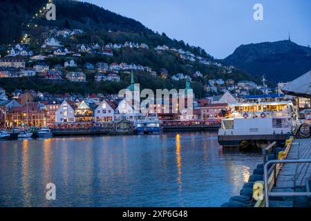 Bergen, Norvegia - 30 aprile 2024: Bergen, l'iconico Bryggen Quay norvegese con i suoi colorati edifici in legno, è affollata di gente. Le barche sono attraccate Foto Stock