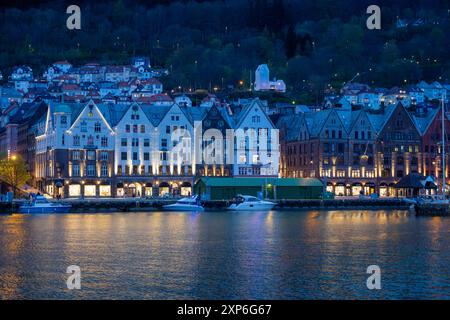 Bergen, Norvegia - 30 aprile 2024: Bergen, l'iconico Bryggen Quay norvegese con i suoi colorati edifici in legno, è affollata di gente. Le barche sono attraccate Foto Stock