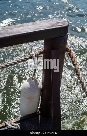 Ringhiera in legno con parafango sopra le acque scintillanti in estate. Foto Stock