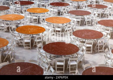 File di tavoli e sedie rotondi disposti in una sala luminosa in attesa degli ospiti. Foto Stock