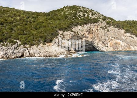 Esplora la grotta del mare di Meganisi Papanikolis nell'isola di Lefkada in Grecia, vicino a Nydri in una crociera in barca, con cielo blu e onde Foto Stock