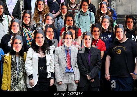 Edimburgo, Scozia, Regno Unito. 4 agosto 2024. Edinburgh Fringe: Un flashmob che indossa le maschere dell'iconica Lynn Benfield, l'assistente di Alan Partridge, sul Royal Mile promuovendo la nuova commedia Lynn Faces della drammaturgo Laura Horton. Mostra alla sala principale di Summerhall, luogo 26, da stasera. Crediti: Craig Brown/Alamy Live News Foto Stock