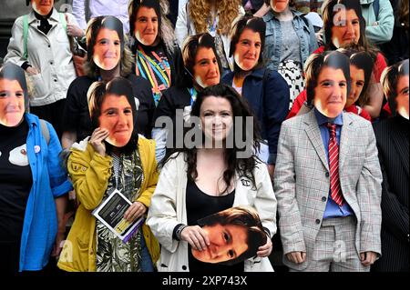 Edimburgo, Scozia, Regno Unito. 4 agosto 2024. Edinburgh Fringe: Un flashmob che indossa le maschere dell'iconica Lynn Benfield, l'assistente di Alan Partridge, sul Royal Mile promuovendo la nuova commedia Lynn Faces della drammaturgo Laura Horton. Mostra alla sala principale di Summerhall, luogo 26, da stasera. Laura Horton ha smascherato il centro illustrato. Crediti: Craig Brown/Alamy Live News Foto Stock