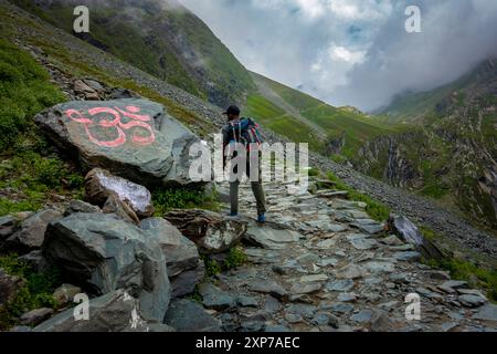 July25th2024, Himachal Pradesh, India. Un devoto che passa accanto a un segno di Om inciso su una pietra durante il mani Mahesh Kailash Yatra nella valle di Chamba, in alto Foto Stock