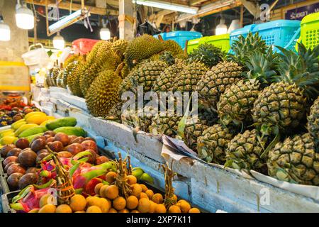 Varietà di frutta tropicale fresca esposta in un bancone del mercato. Colorato spettacolo di duri freschi, ananas, mango, longan e frutti della passione a. Foto Stock