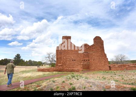 L'uomo cammina lungo il sentiero verso le rovine della missione Quarai e del Convento, presso il Salinas Pueblo National Monument, nel New Mexico. La missione Red Sandstone è Foto Stock