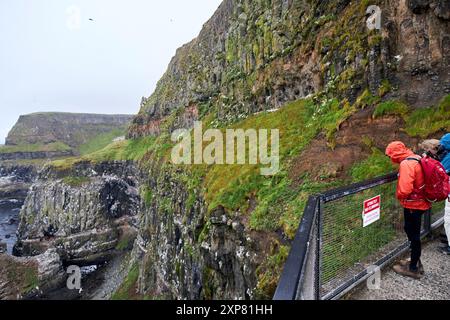 turisti che guardano attraverso il binocolo al centro rspb faro a luce ovest rathlin island, contea di antrim, irlanda del nord, regno unito Foto Stock