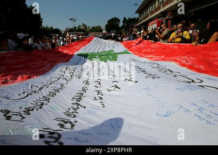 Beirut, Beirut, Libano. 4 agosto 2024. Una grande bandiera libanese è trasportata da madri e parenti, caduti vittime nel 4 agosto 2020 a Beirut, durante il mese di marzo a Beirut in occasione del quarto anniversario dell'esplosione che ha ucciso più di 200 persone e ferito più di 6.000 persone. L'esplosione del porto di domenica arriva mentre la regione si prepara a ritorsioni dopo che uno sciopero israeliano ha ucciso un comandante di Hezbollah a Beirut e un'esplosione a Teheran, ampiamente accusata di Israele, ha ucciso il leader di Hamas Ismail Haniyeh. (Credit Image: © Marwan Naamani/ZUMA Press Wire) UTILIZZO EDITORIALE SU Foto Stock