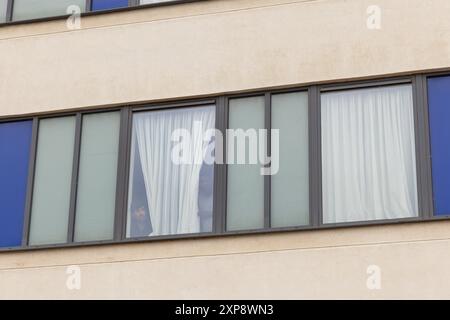 Rotherham, Regno Unito. 04 AGOSTO 2024. I migranti alloggiati nell'hotel guardano fuori dalle finestre verso la folla mentre centinaia di poliziotti e manifestanti si scontrano fuori da un Holiday Inn Express a Manvers Way, Rotherham. I manifestanti di destra, descritti da Sir Kier Starmer come "delinquenti", hanno dato fuoco alla proprietà, hanno distrutto il vetro e hanno combattuto con la polizia per diverse ore. Arresti multipli e feriti a rivoltosi e polizia. Credito Milo Chandler/Alamy Live News Foto Stock