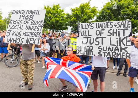 Rotherham, Regno Unito. 04 AGOSTO 2024. Gli uomini hanno dei cartelli che fanno riferimento a Enoch Powell mentre centinaia di poliziotti e manifestanti si scontrano fuori da un Holiday Inn Express a Manvers Way, Rotherham. I manifestanti di destra, descritti da Sir Kier Starmer come "delinquenti", hanno dato fuoco alla proprietà, hanno distrutto il vetro e hanno combattuto con la polizia per diverse ore. Arresti multipli e feriti a rivoltosi e polizia. Un piccolo contigente SUTR che è venuto a sostenere i migranti è stato rimosso dalla polizia per la loro sicurezza. Credito Milo Chandler/Alamy Live News Foto Stock