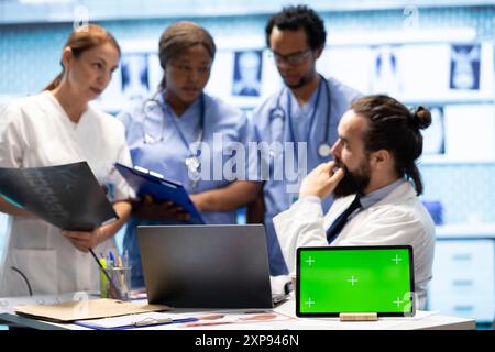 Diversi team di specialisti che esaminano le scansioni di test radiografici con schermo isolato in una riunione, esaminando i risultati dei raggi X in un centro di trattamento. Personale professionale che garantisce la prevenzione delle malattie. Foto Stock