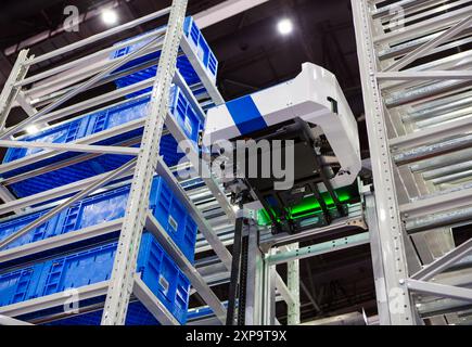 Robot autonomo che preleva i materiali da rack multistrato in un moderno magazzino industriale. Foto Stock
