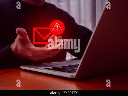 Attacco scammer con il concetto di comunicazione online di spam phishing tramite sms. Busta rossa con l'icona di avviso nella mano dell'hacker che utilizza il cyberattac del computer portatile Foto Stock