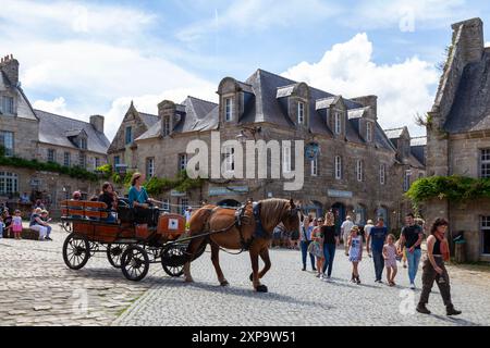 Locronan, Francia - 17 agosto 2023: Carrozza trainata da cavalli che porta i turisti attraverso il centro della città. Foto Stock