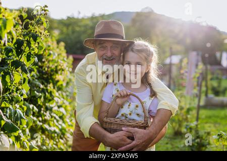 Ritratto di nonno con nipote nipote che raccoglie i rasoi dal cespuglio, trascorrendo del tempo all'aperto in giardino. Foto Stock