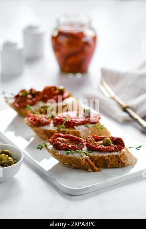 Bruschetta con pomodori secchi e capperi su tavola di marmo Foto Stock