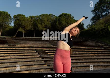 Giovane donna rossa che fa yoga e Pilates in un ambiente naturale con il sole che splende. Foto Stock