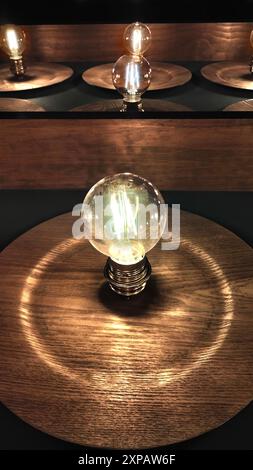 Una lampadina è accesa in una piastra di legno. La luce è calda e invitante, creando un'atmosfera accogliente Foto Stock