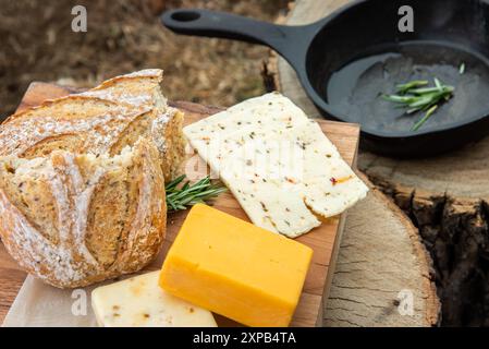 Pane rustico, formaggio e rosmarino con padella su legno surfato Foto Stock