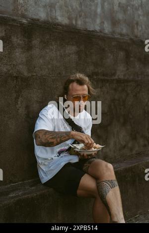 Un uomo che mangia cibo locale a Bali. Foto Stock