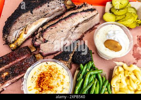 Barbecue texano - petto, costolette di maiale e manzo, crema di mais, mac e formaggio, sottaceti, budino di fagioli e banana, Terry Black's BBQ, Austin, Texas Foto Stock