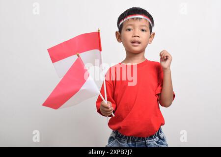 Un ragazzo asiatico felice in maglietta rossa alzando le mani con espressione felice e di successo, isolato su sfondo bianco. Giorno dell'indipendenza indonesiana Foto Stock