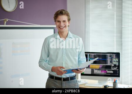Un giovane professionista sorridente che presenta in un ambiente Office Foto Stock