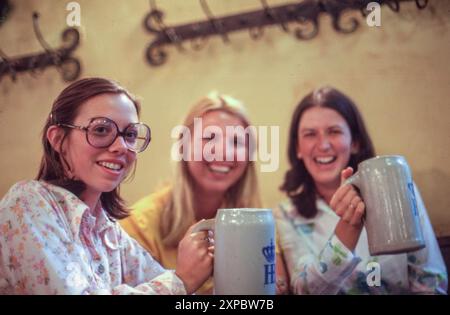 Tre hostess Pan Am che si godono le birre all'Oktoberfest in Germania, Monaco di Baviera, 1974. Foto Stock