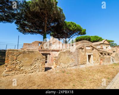 Edifici funerari di una o due piani quadrati, spesso circondati da un recinto; soffitti a botte o tetti piatti; facciate in mattoni adornate con timpani triangolari, plinti, lesbiche, colonne e capitelli; piccole finestre e porte incorniciate da soglie in travertino, stipiti ed epistoli. La necropoli si sviluppò ai lati della via Flavia tra la fine del i e il IV secolo d.C. - Necropoli di Portus nell'Isola Sacra, Fiumicino, Roma, Italia Foto Stock