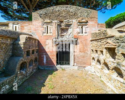 Edificio sepolcrale di una o due piani, spesso circondato da un recinto; soffitti a botte o tetti piatti; facciate in mattoni adornate con timpani triangolari, plinti, lesbiche, colonne e capitelli; piccole finestre e porte incorniciate da soglie in travertino, stipiti ed epistoli. La necropoli si sviluppò ai lati della via Flavia tra la fine del i e il IV secolo d.C. - Necropoli di Portus nell'Isola Sacra, Fiumicino, Roma, Italia Foto Stock