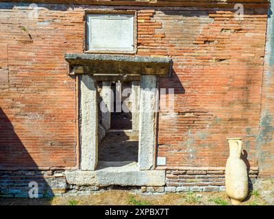 Edificio sepolcrale di una o due piani, spesso circondato da un recinto; soffitti a botte o tetti piatti; facciate in mattoni adornate con timpani triangolari, plinti, lesbiche, colonne e capitelli; piccole finestre e porte incorniciate da soglie in travertino, stipiti ed epistoli. La necropoli si sviluppò ai lati della via Flavia tra la fine del i e il IV secolo d.C. - Necropoli di Portus nell'Isola Sacra, Fiumicino, Roma, Italia Foto Stock