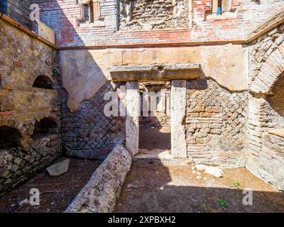 Edificio sepolcrale di una o due piani, spesso circondato da un recinto; soffitti a botte o tetti piatti; facciate in mattoni adornate con timpani triangolari, plinti, lesbiche, colonne e capitelli; piccole finestre e porte incorniciate da soglie in travertino, stipiti ed epistoli. La necropoli si sviluppò ai lati della via Flavia tra la fine del i e il IV secolo d.C. - Necropoli di Portus nell'Isola Sacra, Fiumicino, Roma, Italia Foto Stock