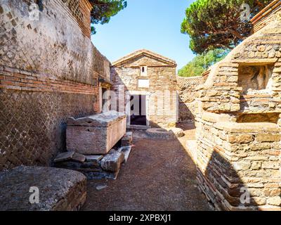 Edificio sepolcrale di una o due piani, spesso circondato da un recinto; soffitti a botte o tetti piatti; facciate in mattoni adornate con timpani triangolari, plinti, lesbiche, colonne e capitelli; piccole finestre e porte incorniciate da soglie in travertino, stipiti ed epistoli. La necropoli si sviluppò ai lati della via Flavia tra la fine del i e il IV secolo d.C. - Necropoli di Portus nell'Isola Sacra, Fiumicino, Roma, Italia Foto Stock