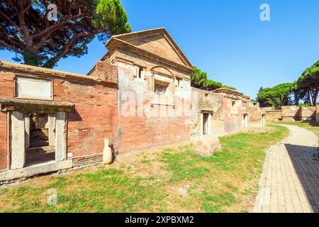 Edifici funerari di una o due piani quadrati, spesso circondati da un recinto; soffitti a botte o tetti piatti; facciate in mattoni adornate con timpani triangolari, plinti, lesbiche, colonne e capitelli; piccole finestre e porte incorniciate da soglie in travertino, stipiti ed epistoli. La necropoli si sviluppò ai lati della via Flavia tra la fine del i e il IV secolo d.C. - Necropoli di Portus nell'Isola Sacra, Fiumicino, Roma, Italia Foto Stock