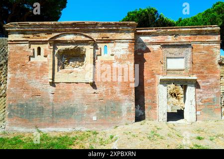 Edificio sepolcrale di una o due piani, spesso circondato da un recinto; soffitti a botte o tetti piatti; facciate in mattoni adornate con timpani triangolari, plinti, lesbiche, colonne e capitelli; piccole finestre e porte incorniciate da soglie in travertino, stipiti ed epistoli. La necropoli si sviluppò ai lati della via Flavia tra la fine del i e il IV secolo d.C. - Necropoli di Portus nell'Isola Sacra, Fiumicino, Roma, Italia Foto Stock