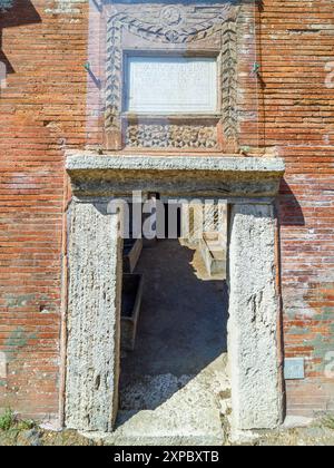 Edificio sepolcrale di una o due piani, spesso circondato da un recinto; soffitti a botte o tetti piatti; facciate in mattoni adornate con timpani triangolari, plinti, lesbiche, colonne e capitelli; piccole finestre e porte incorniciate da soglie in travertino, stipiti ed epistoli. La necropoli si sviluppò ai lati della via Flavia tra la fine del i e il IV secolo d.C. - Necropoli di Portus nell'Isola Sacra, Fiumicino, Roma, Italia Foto Stock