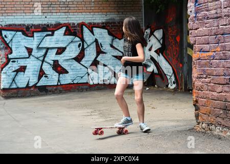 Mosca, Russia - 13 maggio 2018: Uno skateboarder cavalca in un vicolo adornato di graffiti. Foto Stock