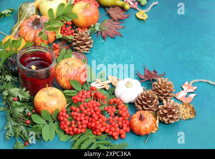 Composizione autunnale con zucche, mele e rowan su sfondo blu vivace con spazio per copie. Decorazioni autunnali ecologiche su un tavolo. Foto Stock