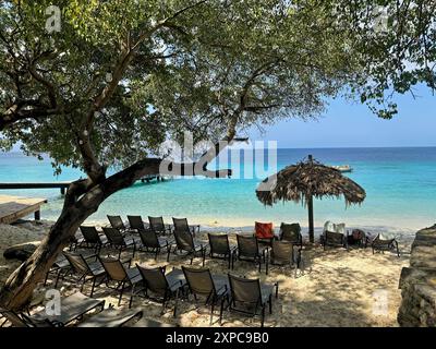 Spiaggia con lettini, ombrellone, molo e vista mare a Curacao Foto Stock