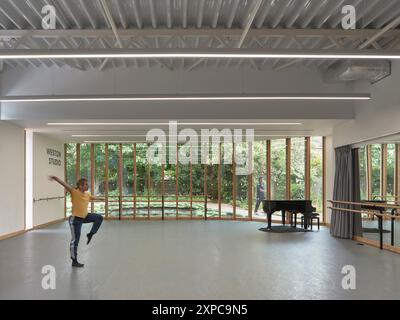 Interni dello studio con ballerino, pianoforte e finestrazioni. Rambert School of Ballet, Londra, Regno Unito. Architetto: MICA, 2023. Foto Stock