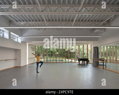 Interni dello studio con ballerino, pianoforte e finestrazioni. Rambert School of Ballet, Londra, Regno Unito. Architetto: MICA, 2023. Foto Stock